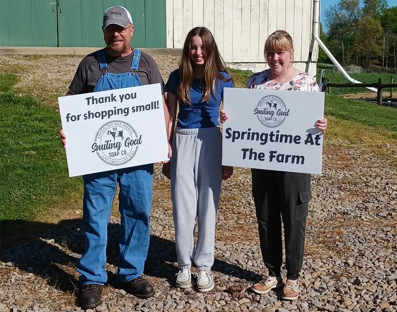 the smiling goat soap company family holding up white custom signs